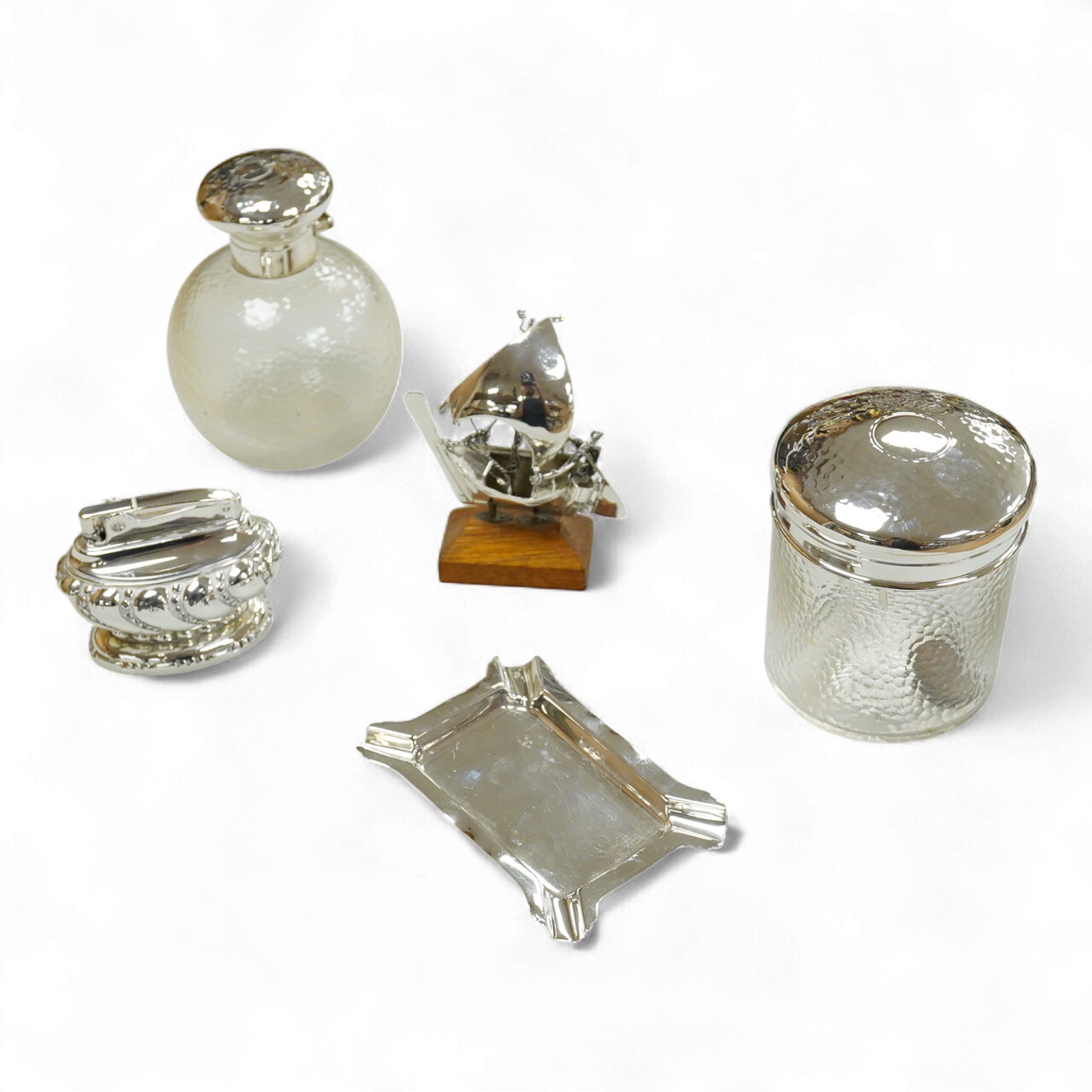 A collection of silver or white metal to include a miniature model dhal, ashtray, scent bottle and toilet jar, together with a metal Ronson table lighter.